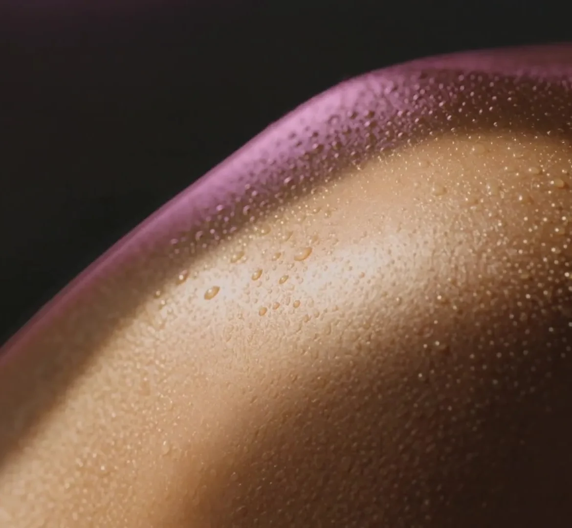 Close-up of glowing, evenly bronzed skin with fine droplets of water