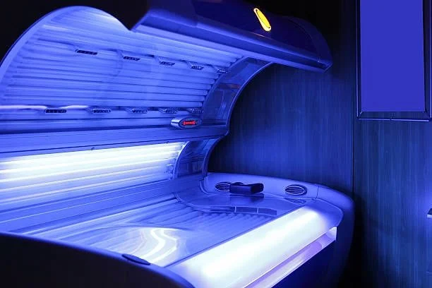 An open tanning bed glowing blue, ready for a session